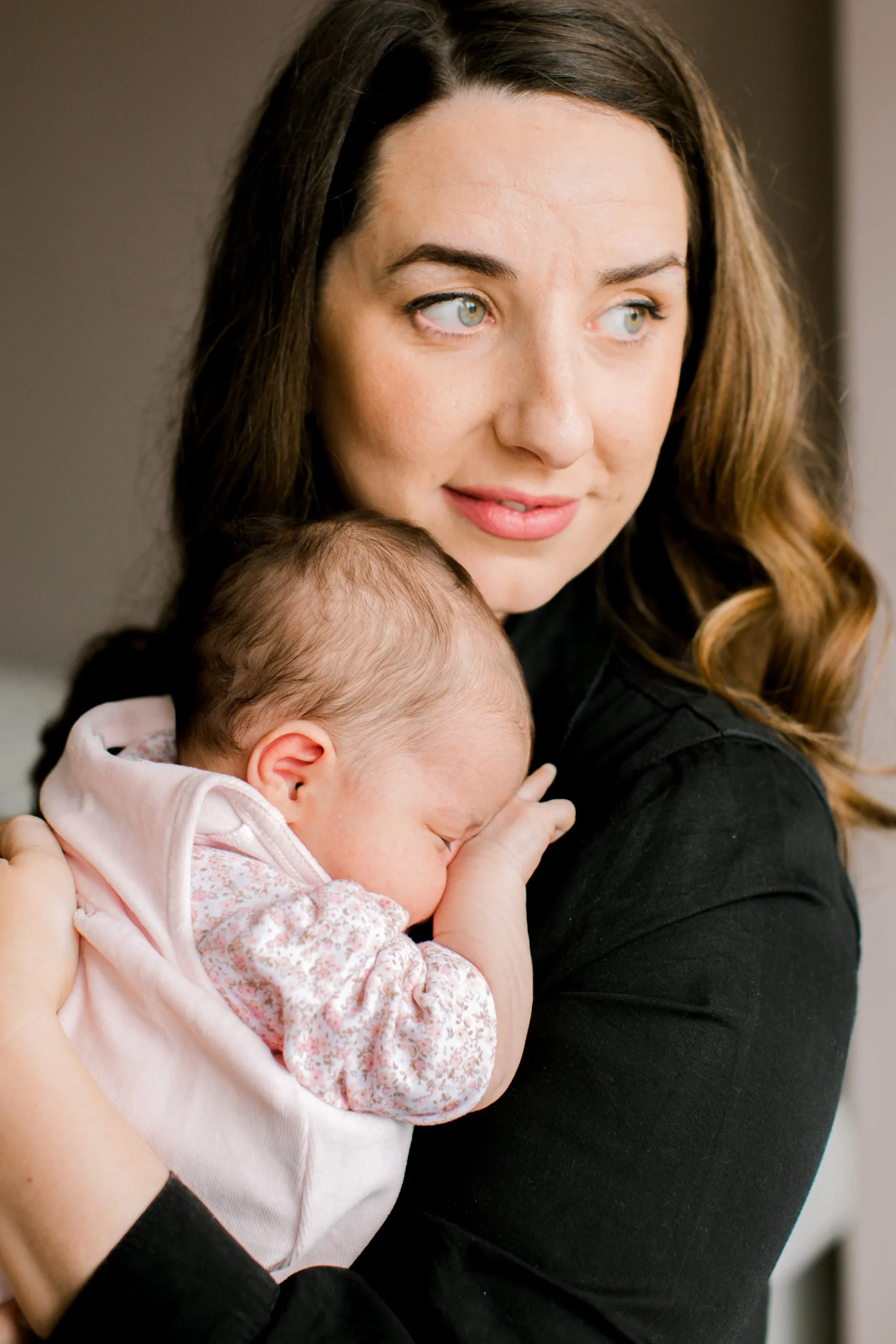 A woman holding a sleeping baby close to her shoulder.